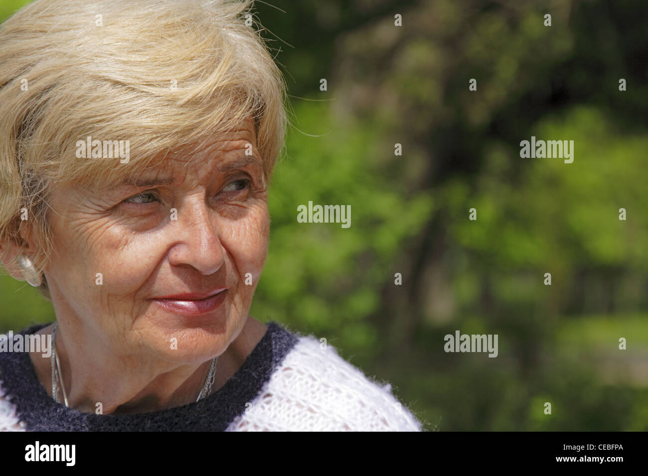 Portrait of a senior woman in a park à la recherche avec l'attention sur quelque chose. Banque D'Images