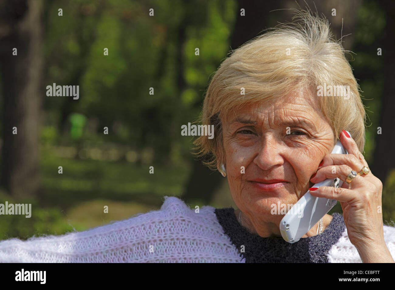 Image d'une femme âgée à l'aide d'un téléphone mobile dans un parc. Banque D'Images