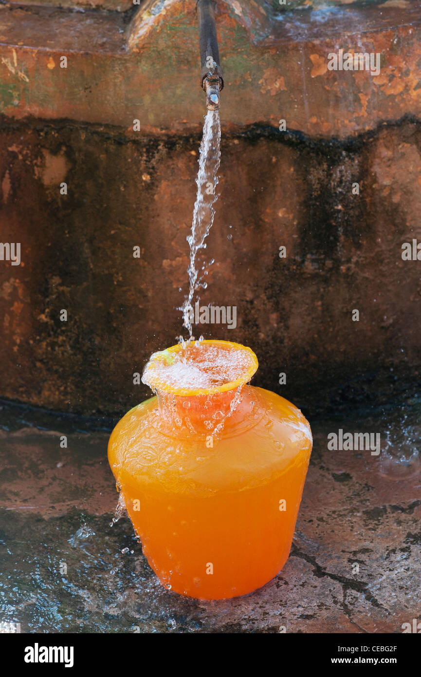 L'eau des indiens à tuyau remplissage d'un pot d'eau en plastique. L'Andhra Pradesh, Inde Banque D'Images