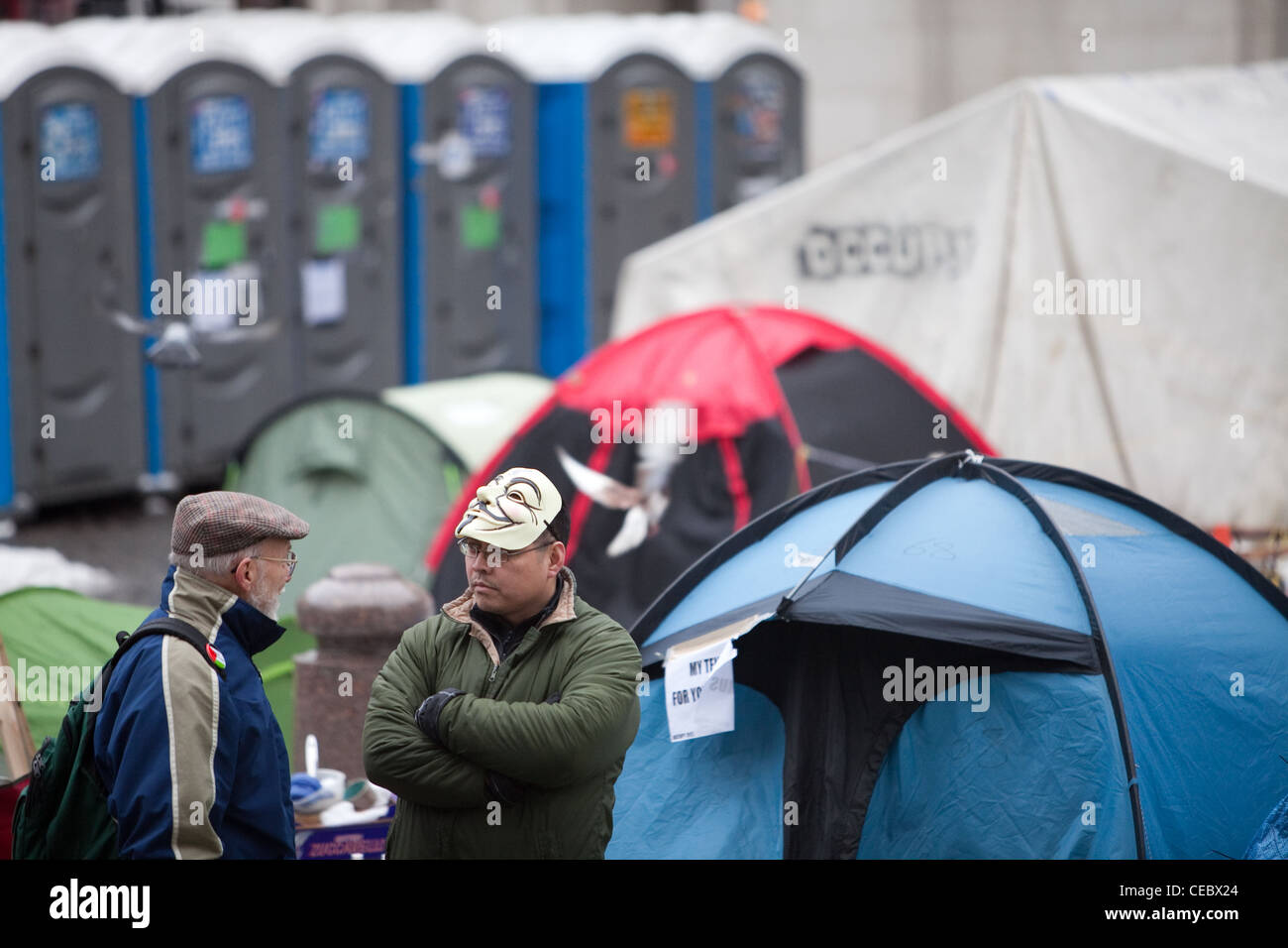 Un activiste dans un masque v pour vendetta parle à un membre du public à l'occupy London camp de St Paul's Cathedral. Banque D'Images