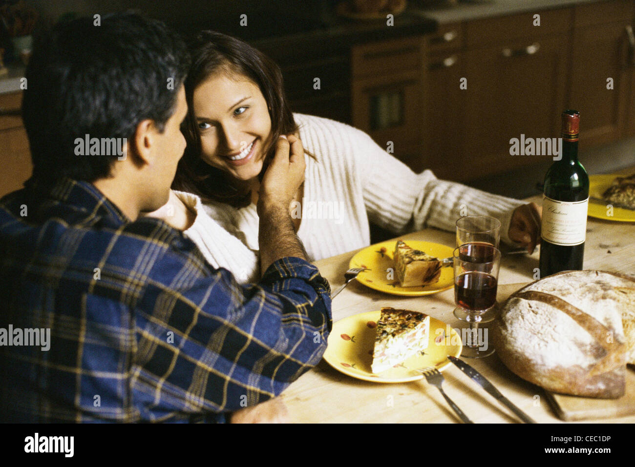 Couple assis à table, l'homme en caressant la joue de la femme Banque D'Images