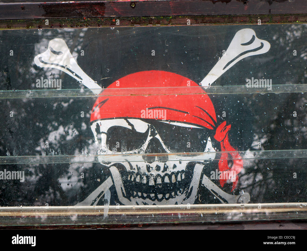 Un Jolly Roger Tête de mort pirates drapeau dans la fenêtre d'un canal barge. Banque D'Images