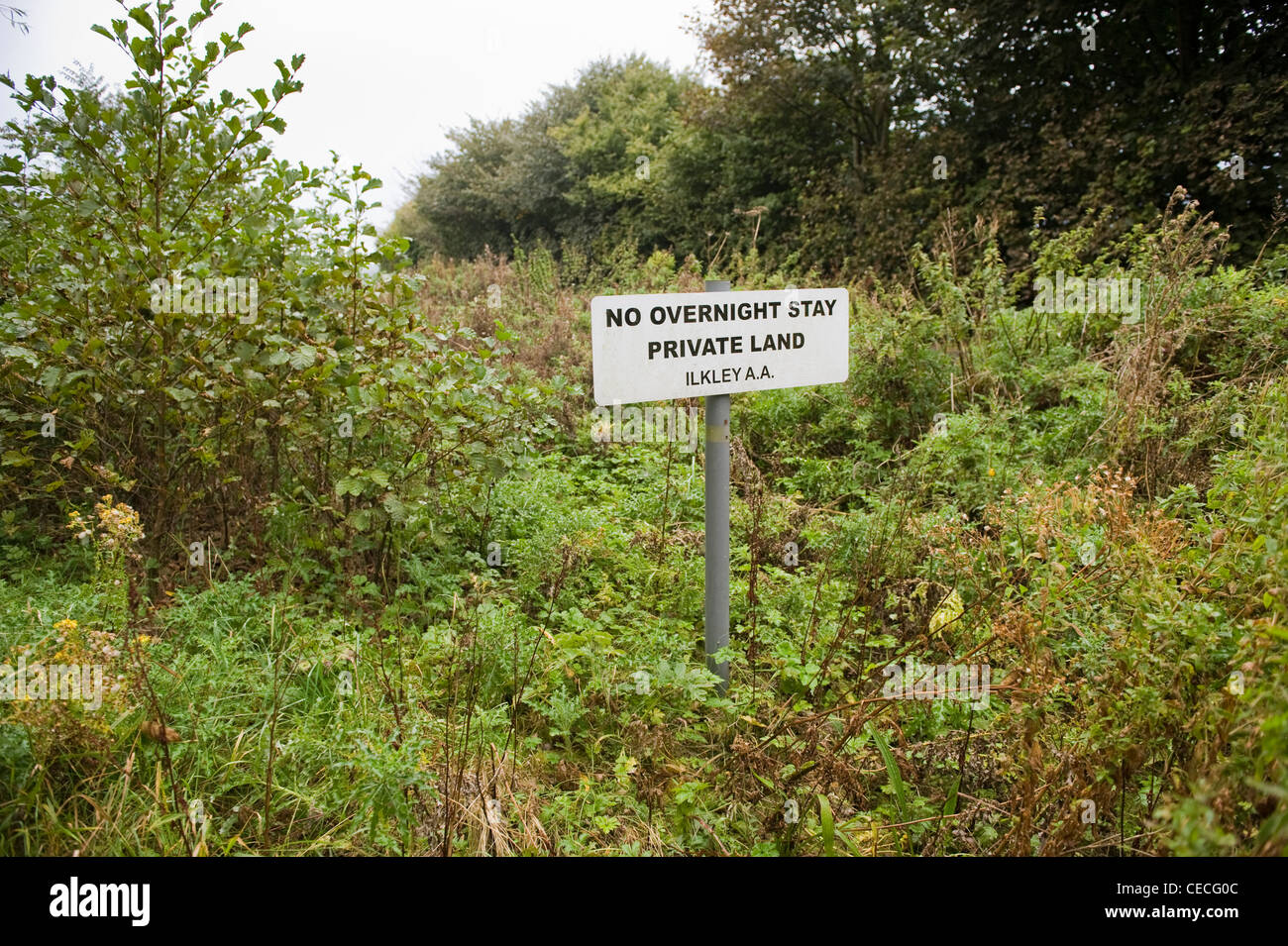 Signe clair & enseigne sur des terres privées (vert) envahi par l'interdiction de stationnement donnant ('information sans nuitée') - Bradford, West Yorkshire, Angleterre, Royaume-Uni. Banque D'Images