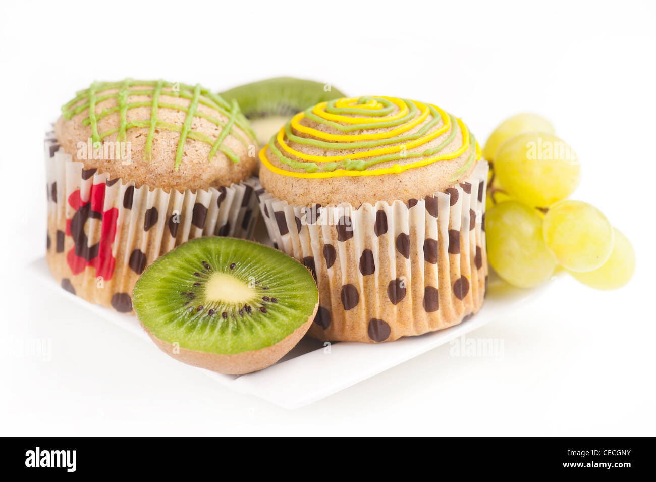 Deux muffins sur plaque blanche avec des raisins et des kiwis sur fond blanc, selective focus Banque D'Images