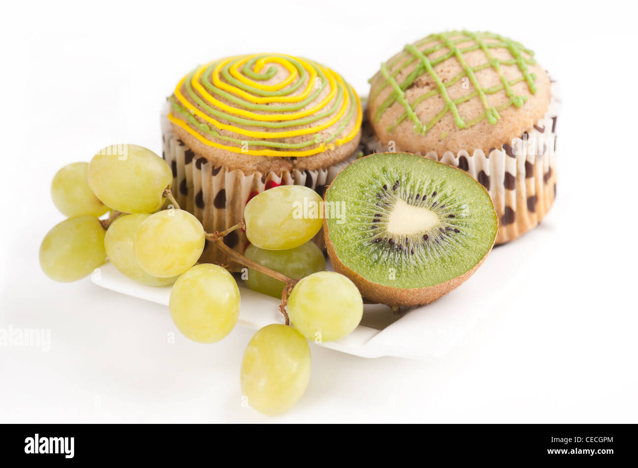 Deux muffins sur plaque blanche avec des raisins et des kiwis sur fond blanc, selective focus Banque D'Images