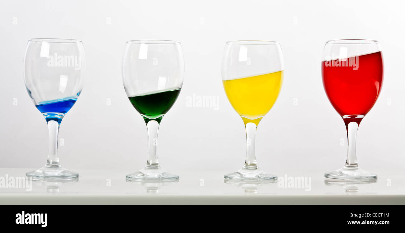 Quatre verres avec différentes quantités de liquide de couleur sur une pente Banque D'Images