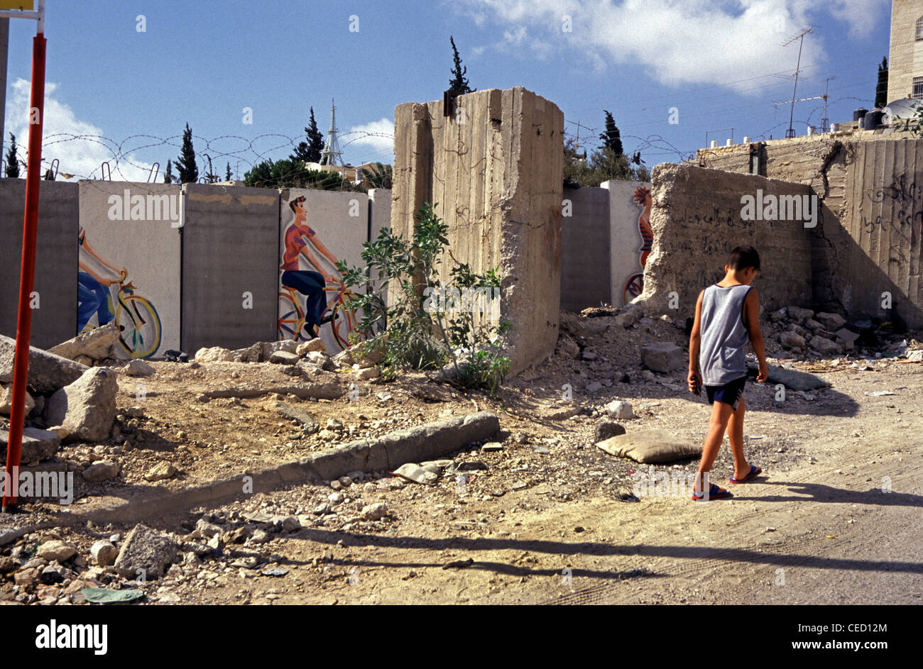 Un enfant palestinien passe devant la barrière de séparation israélienne de Cisjordanie en traversant Abou dis ou Abou dis, une communauté palestinienne appartenant au gouvernorat palestinien de Jérusalem, coupée de Jérusalem par le mur de séparation construit par Israël Banque D'Images