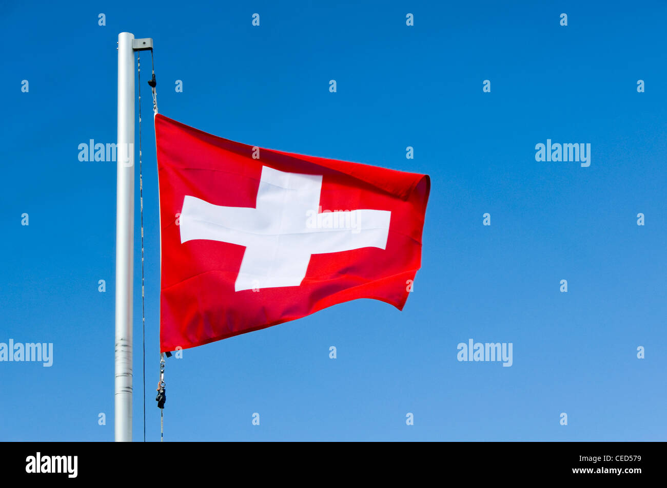 De près de l'horizontale rouge et blanc drapeau suisse à fullmast contre un ciel bleu. Banque D'Images