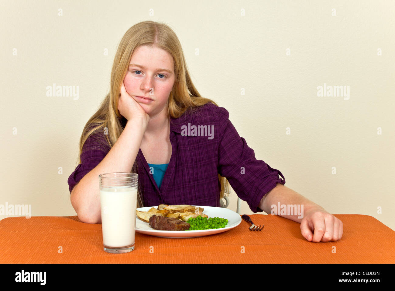 Volonté têtu malheureux Teenage girl Sitting tableau attitude malsaine vers l'Aliment détesté refuse de manger son dîner contact visuel © Myrleen caméra M. Pearson Banque D'Images