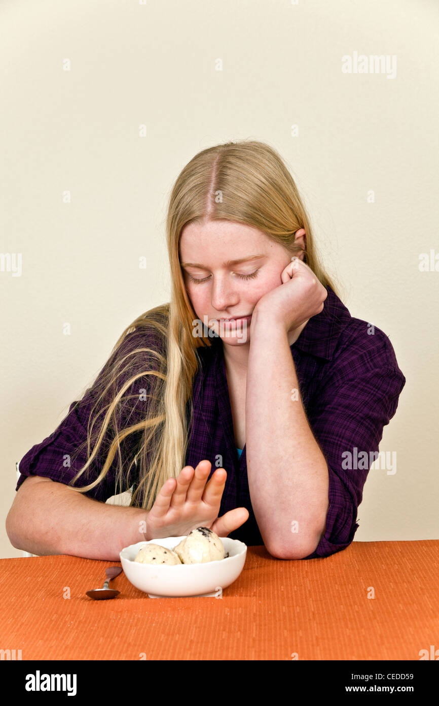 Caucasian 14-16 ans oldsTeenage rif à table avec l'attitude envers les aliments malsains refuse de manger de la crème glacée dessert. M. © Myrleen Pearson Banque D'Images