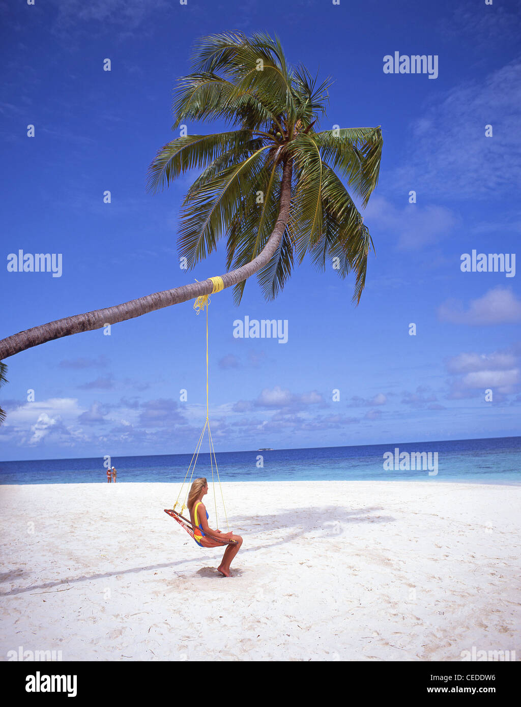 Jeune femme assise sous le palmier, Atoll de Kaafu, Kuda Bandos, République des Maldives Banque D'Images