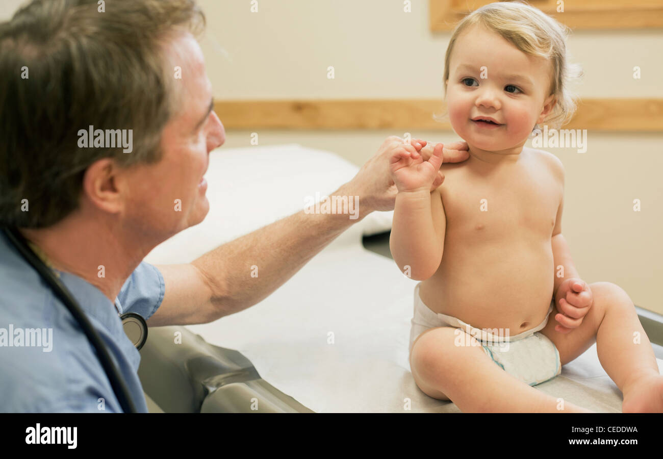 Jeune médecin examine bébé garçon au bureau du médecin. Banque D'Images