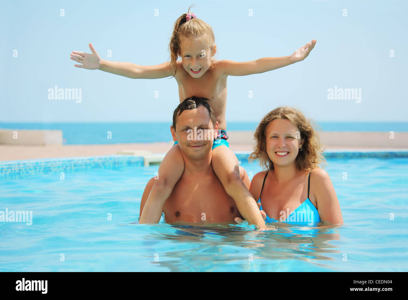 Smiling family en piscine. Fille est assise sur l'épaule de pères Banque D'Images