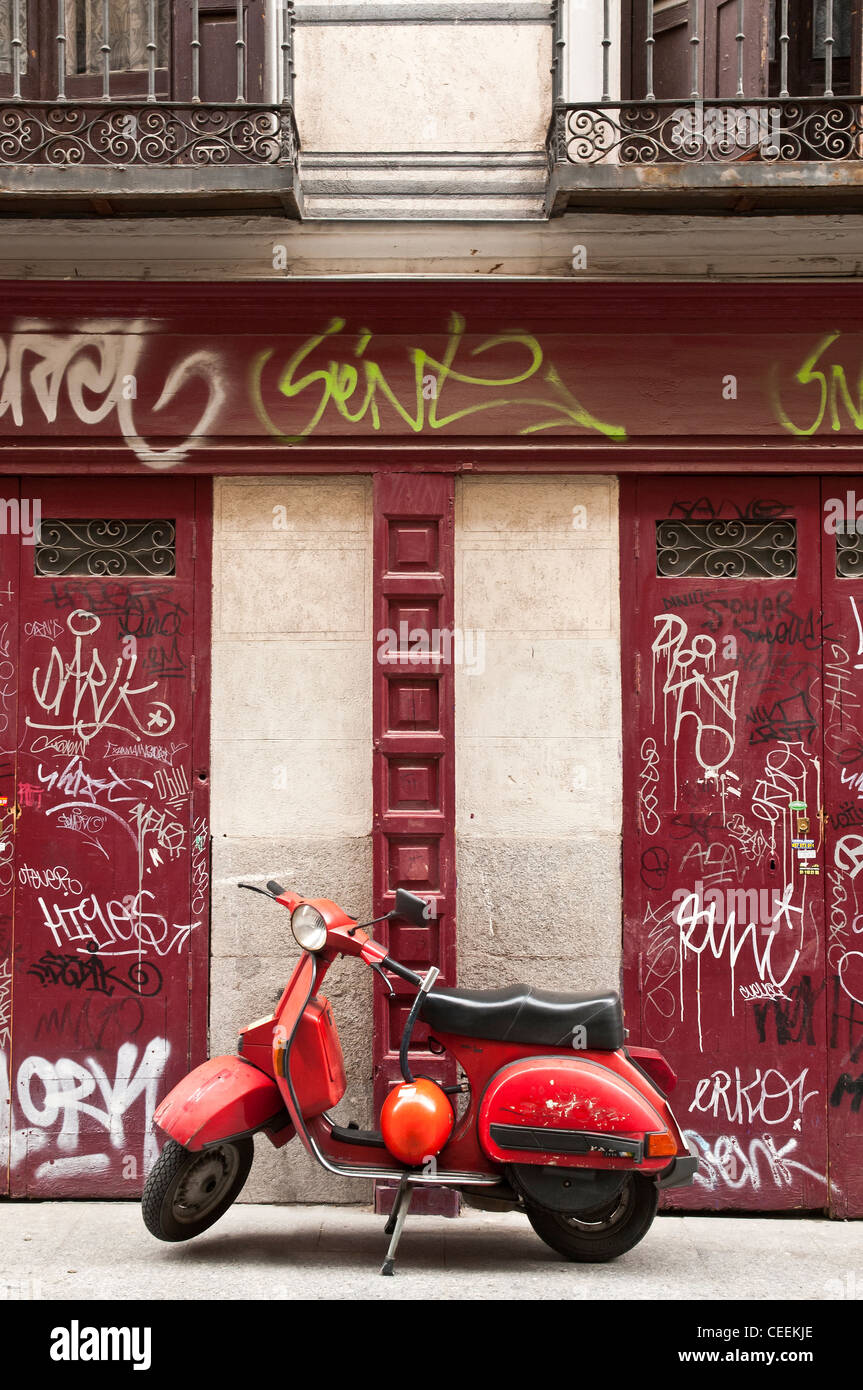 Scooter rouge et couvert de graffitis volets central, Madrid, Espagne Banque D'Images