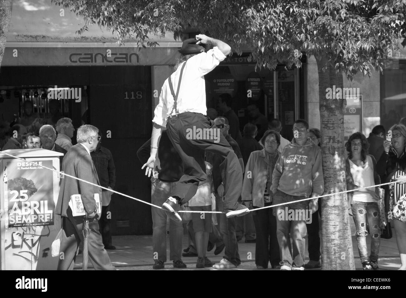 Un homme marche une corde raide tout en spectateurs regarder dans la crainte à Rossio, Lisbonne, Portugal Banque D'Images