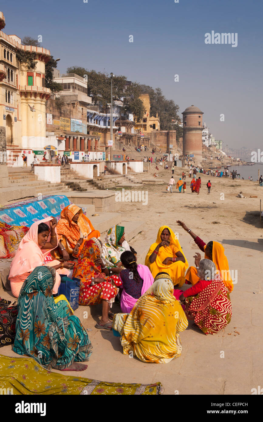 L'Inde, Uttar Pradesh, Varanasi, habillés de couleurs vives les pèlerins assis sur Reewal Ghat étapes au bord de la rivière Ganges Banque D'Images