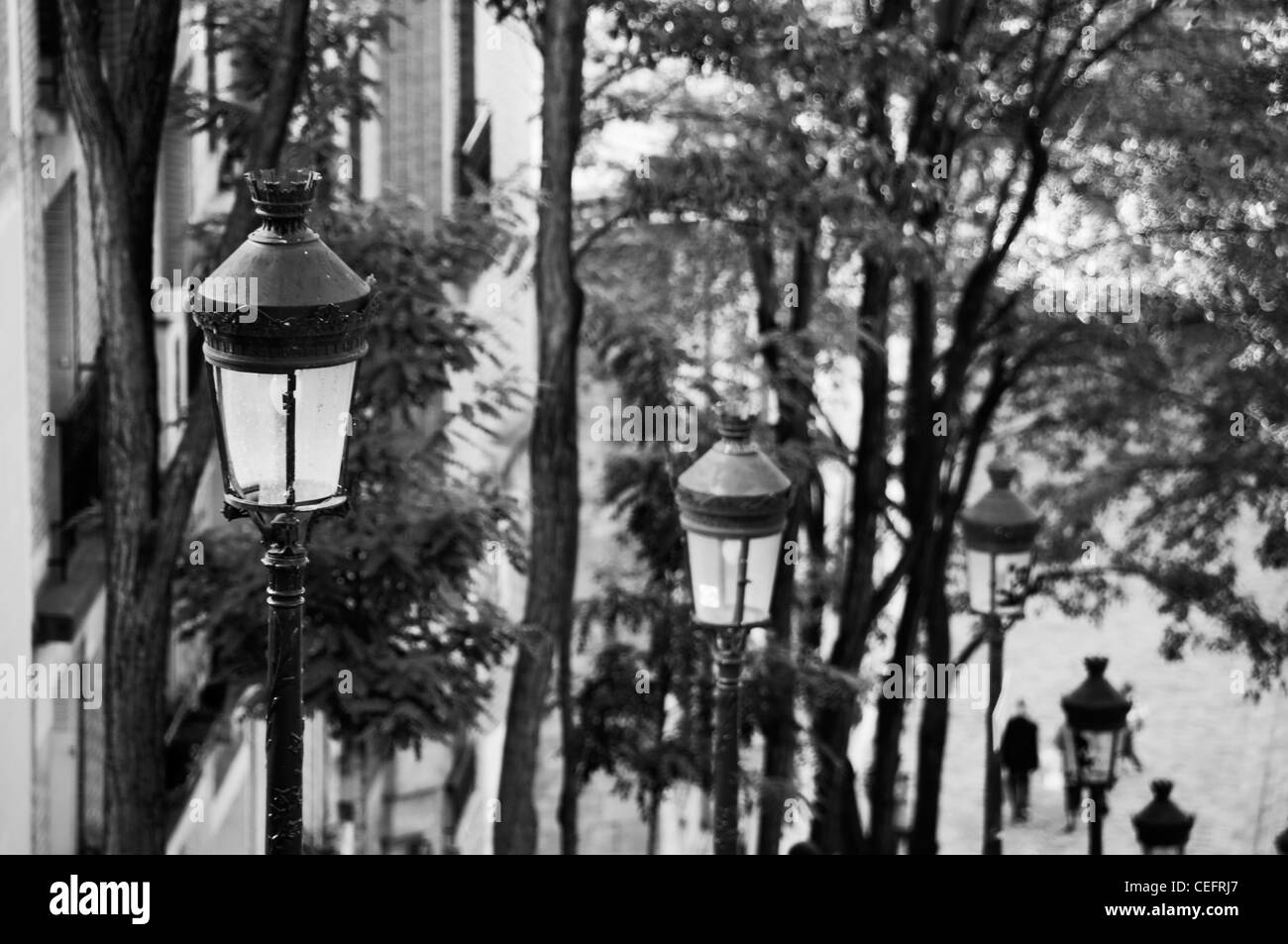 Citylights dans une rue en pente de la Butte Montmartre, Paris - France noir et blanc. Banque D'Images