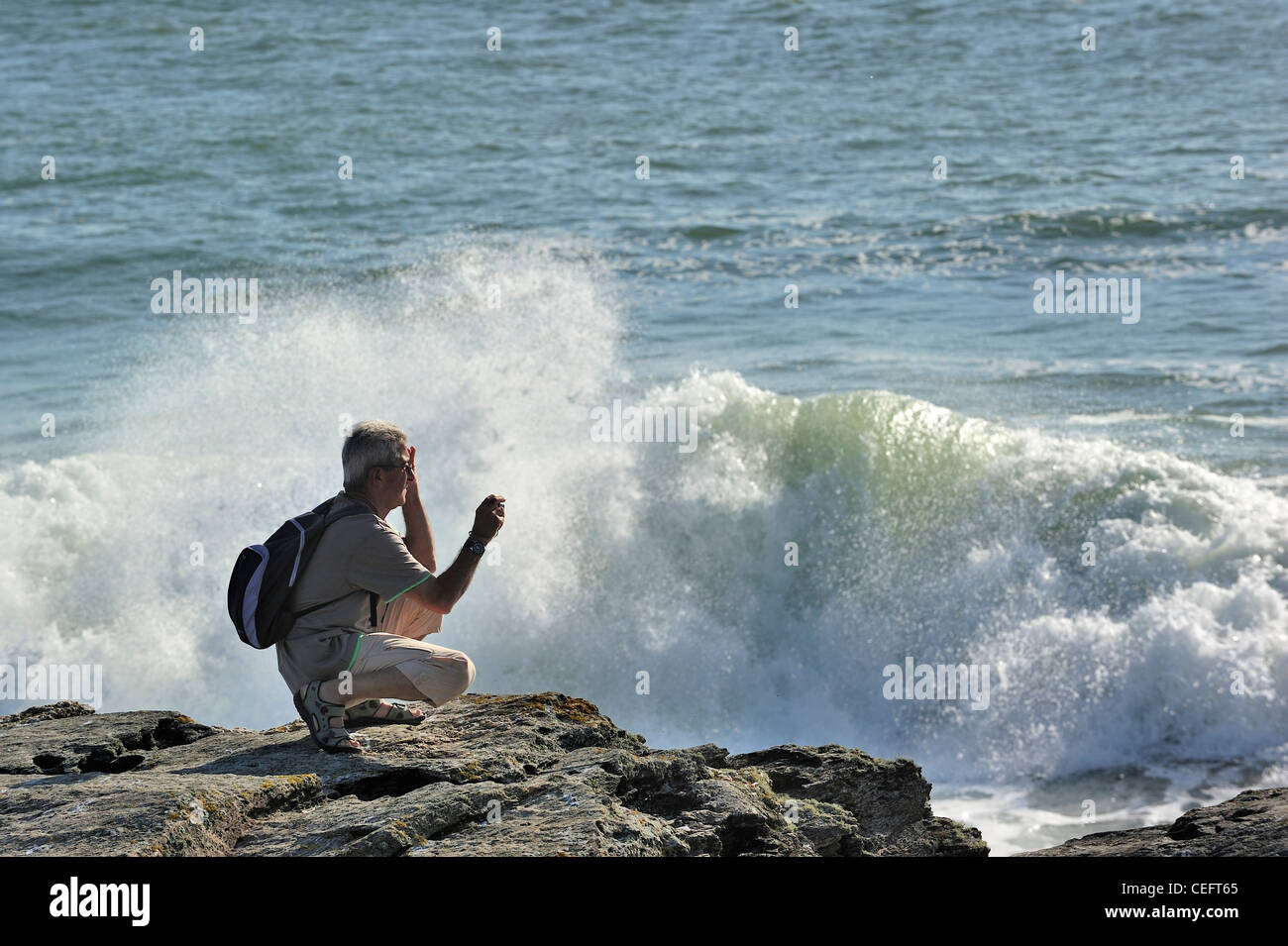 Prise de photos touristiques de vagues se brisant sur les rochers à la Pointe Saint-Gildas / Saint Gildas Point, Loire-Atlantique, France Banque D'Images