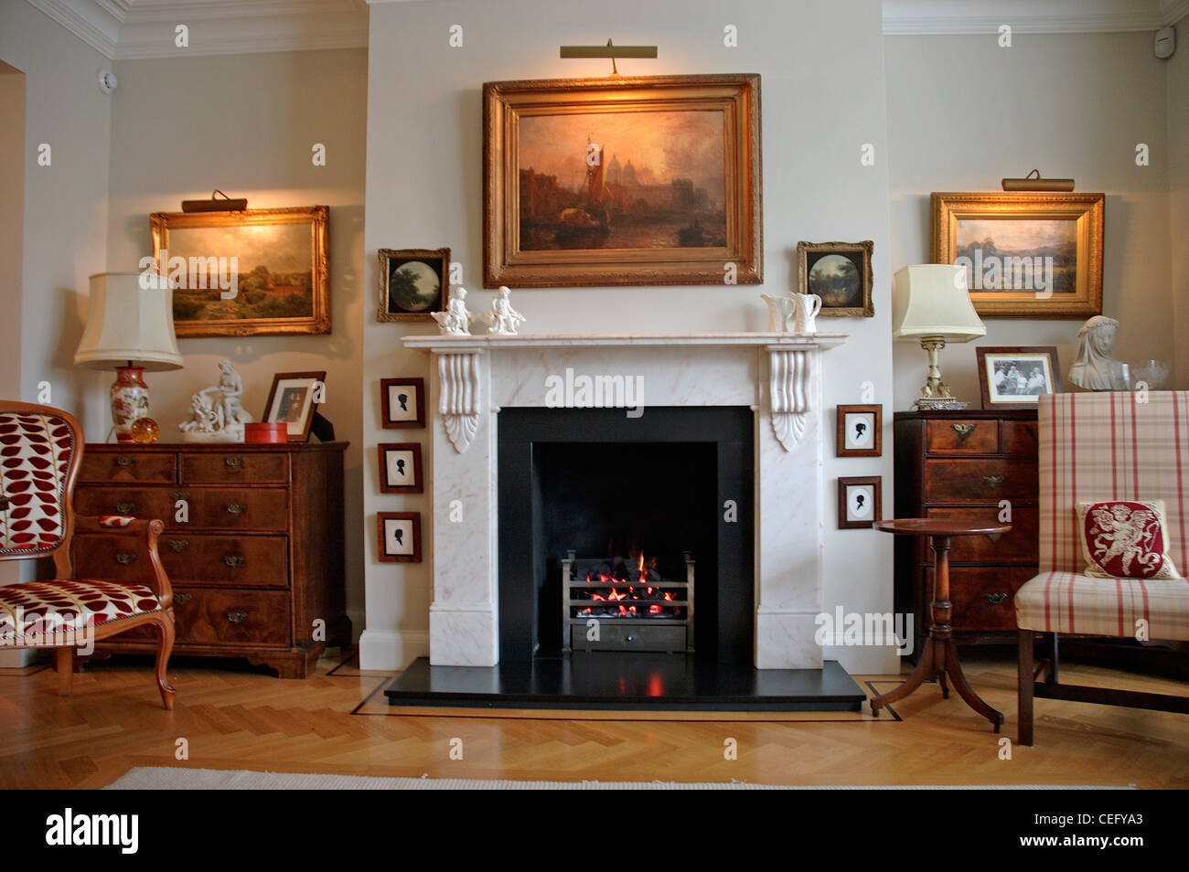 Photo feux au-dessus des peintures dans un salon traditionnel avec cheminée en marbre et de meubles anciens Banque D'Images