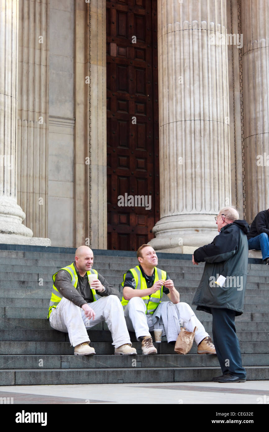 Un protestataire Occupy London parler aux travailleurs de la construction qui sont assis en train de déjeuner sur l'entrée principale étapes de St Paul's Banque D'Images