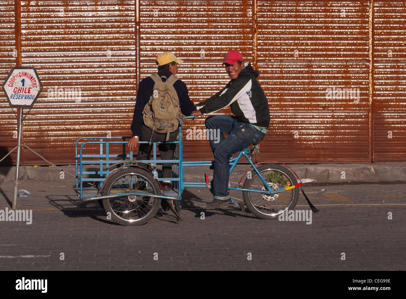 Deux jeunes hommes hispaniques monter un vélo de livraison sur le marché à Latacunga, Equateur. Banque D'Images