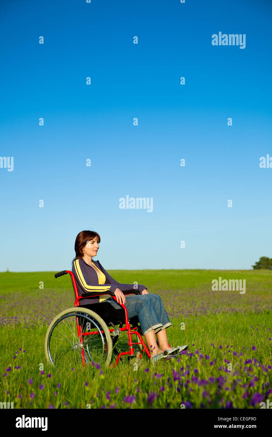 Femme handicapé sur un fauteuil roulant sur un pré vert Banque D'Images