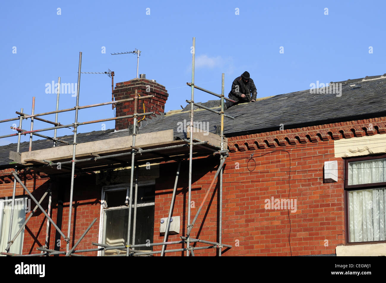 L'homme travaillant sur des échafaudages avec toit à l'avant de la chambre Banque D'Images