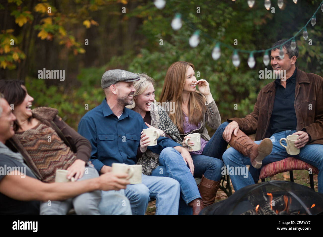 Smiling friends outdoors by fire Banque D'Images