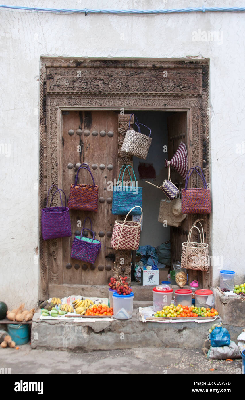 Des sacs colorés et des fruits à vendre, suspendu à une porte traditionnelle de Stone Town, Zanzibar, Tanzanie Banque D'Images