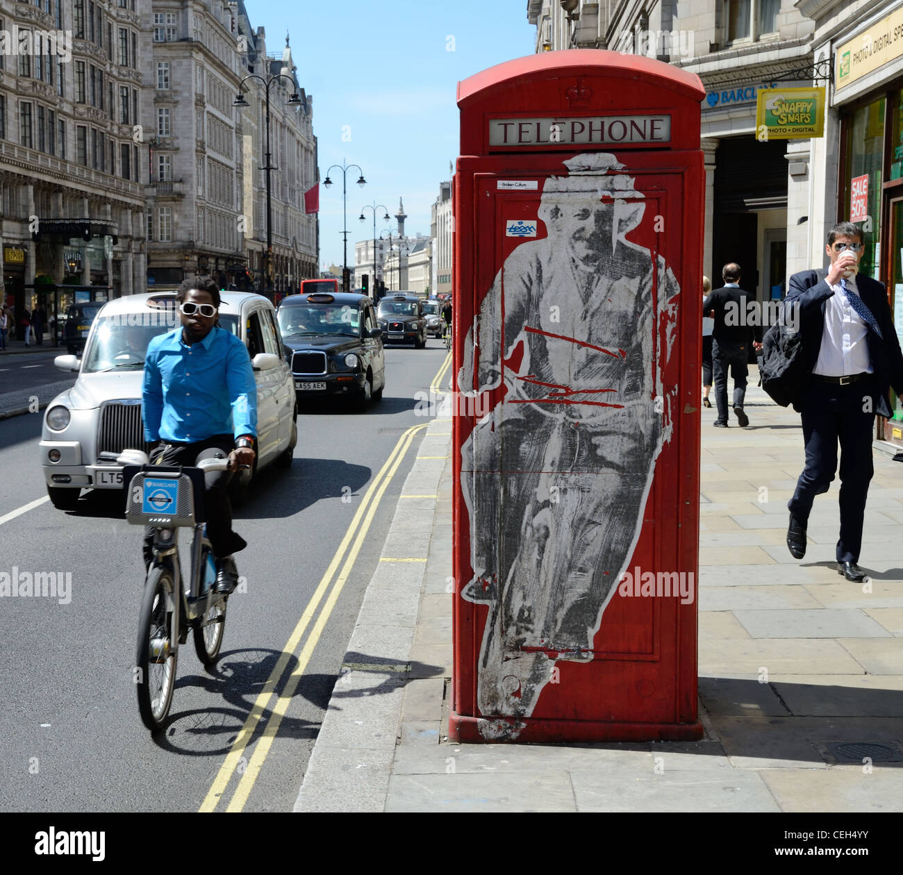 Mec Cool sur un Boris Bike passant un graffiti poster d'Einstein sur un vélo sur une boîte de téléphone rouge, sur le Strand Banque D'Images