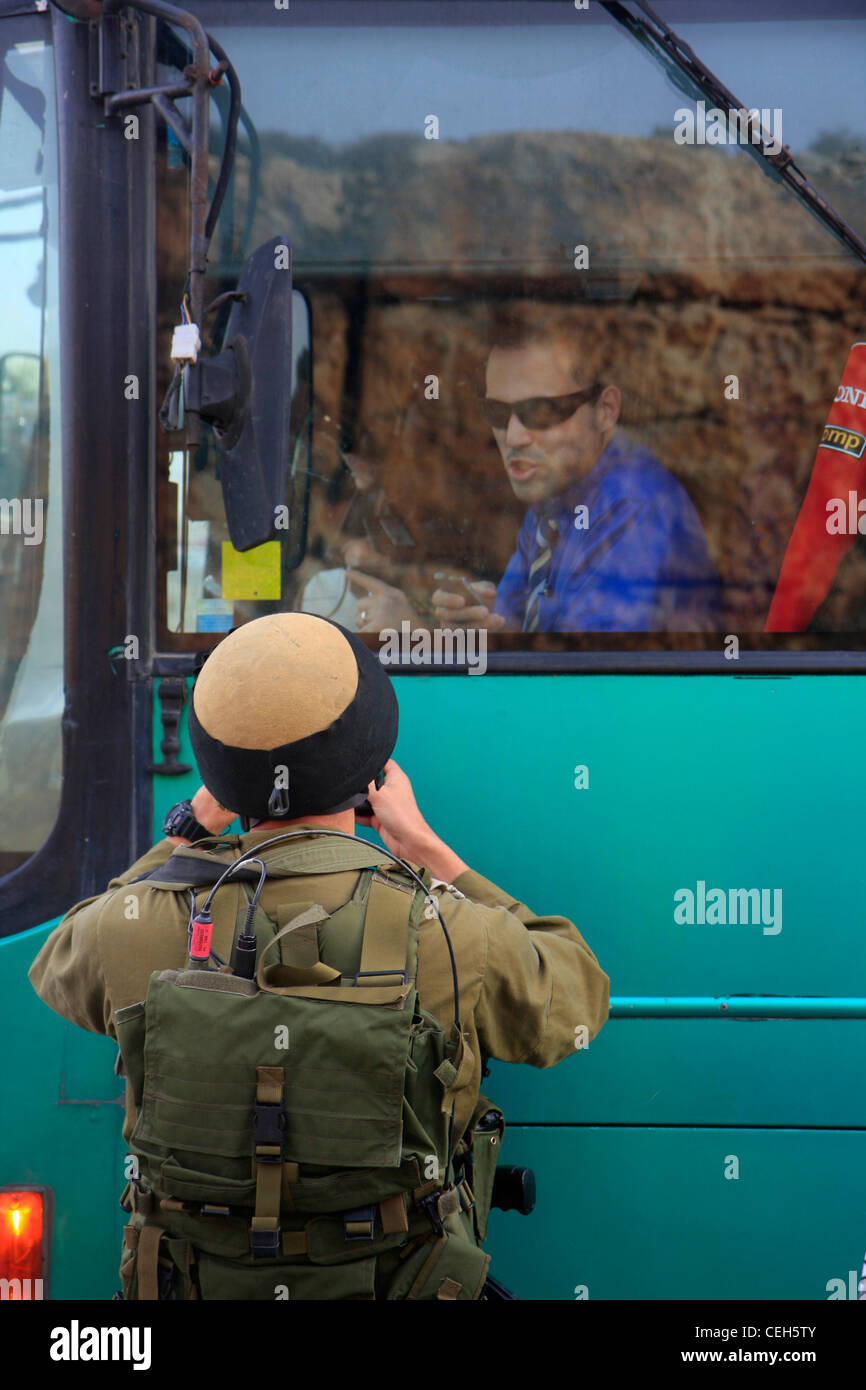 Un soldat israélien utilise un téléphone cellulaire pour communiquer à travers une fenêtre avec un chauffeur de bus Egged. Banque D'Images