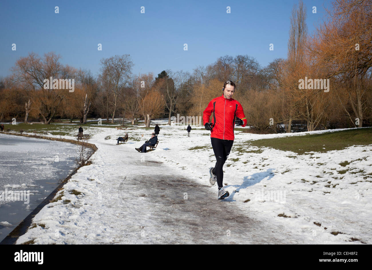 Man jogging on frozen sentier, Hampstead Heath, Highgate, Londres, UK Banque D'Images