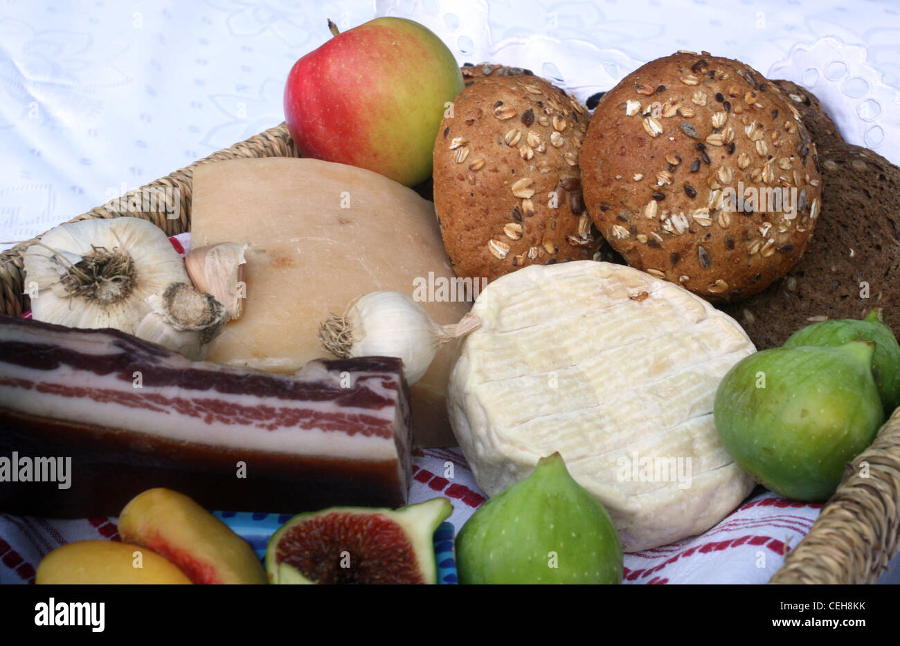 La vie encore rustique de pain, fromage, bacon et figues dans un panier en osier Banque D'Images