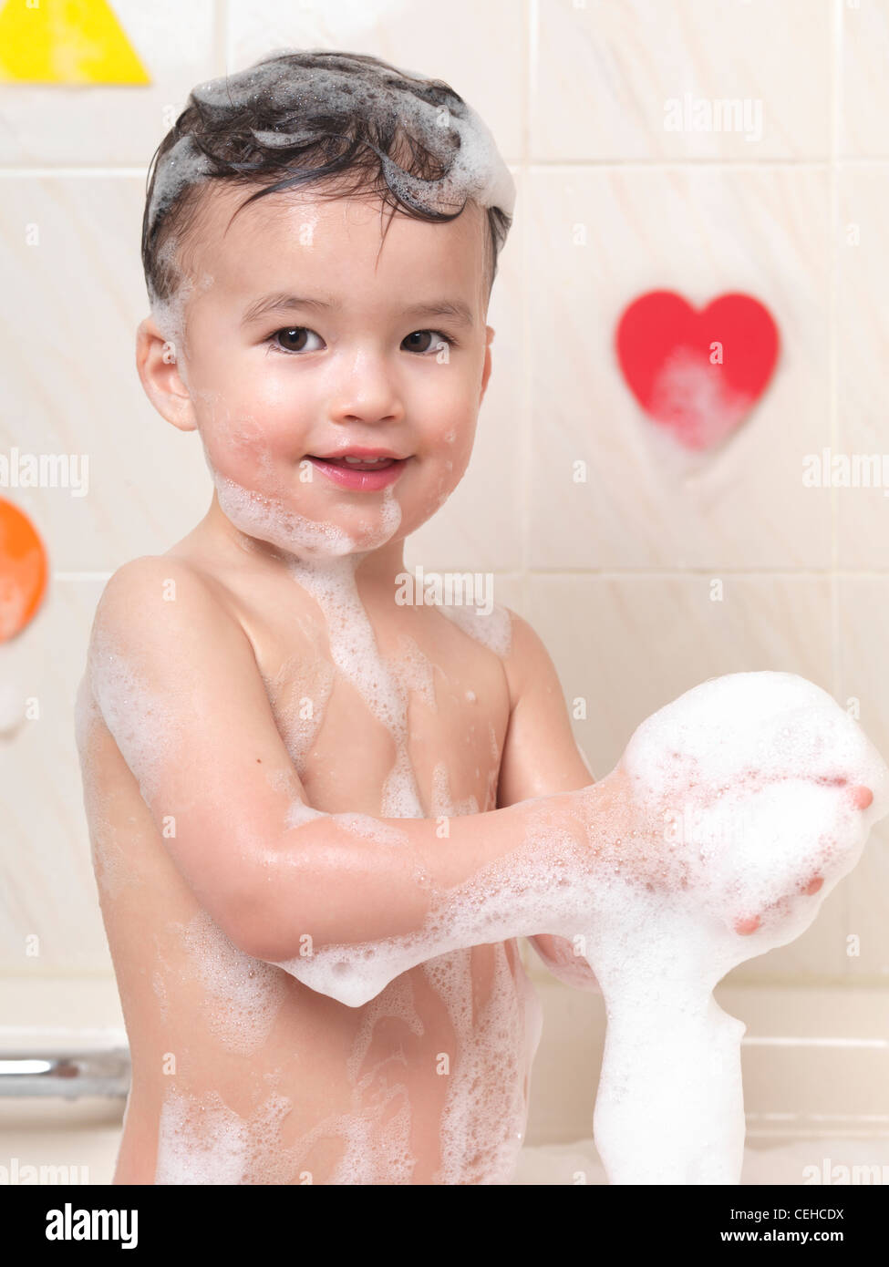 Enfant de deux ans s'amusant dans un bain de mousse Banque D'Images
