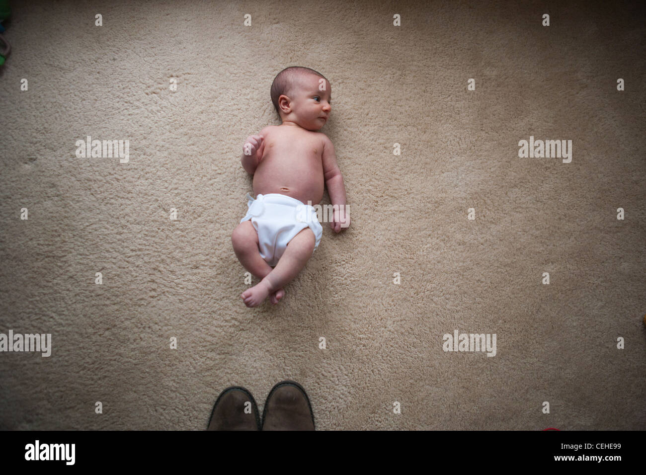 Un bébé nouveau-né fille portant sur le sol en face de la pointe des chaussures, montrant la petite taille de l'enfant. Banque D'Images