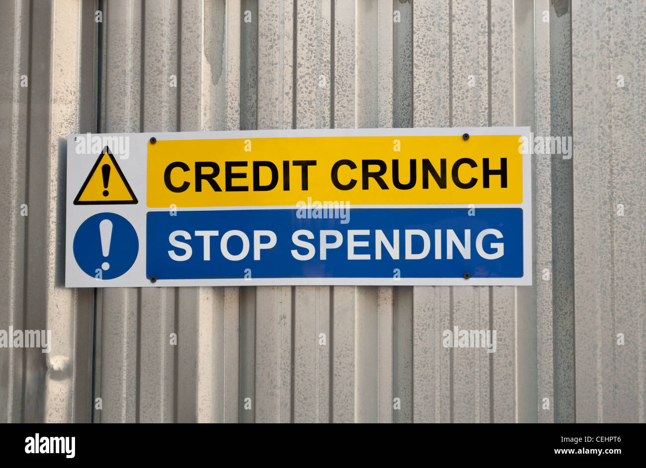 Un panneau d'avertissement jaune et bleu avec les mots de la crise du crédit et cesser de dépenser contre metal background Banque D'Images
