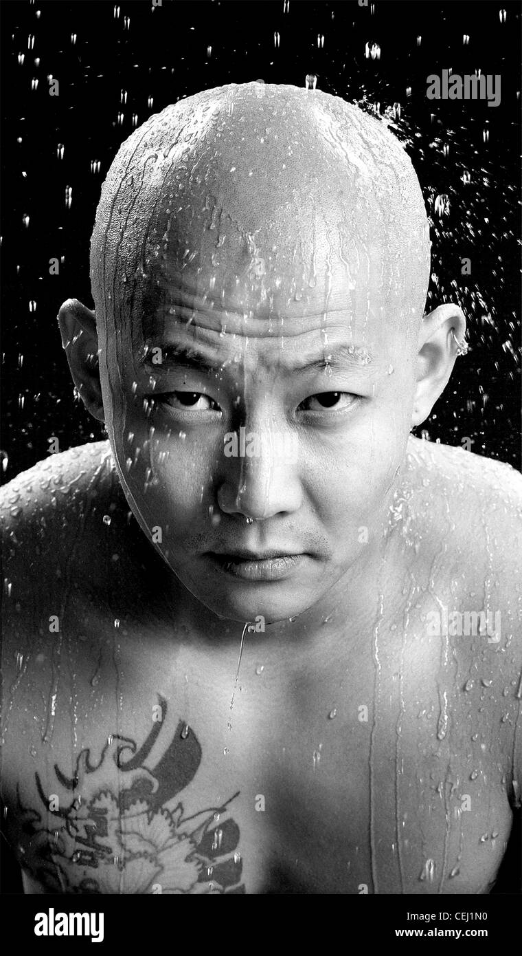 L'eau tombant sur bold asian man with tatouage sur la poitrine. Banque D'Images
