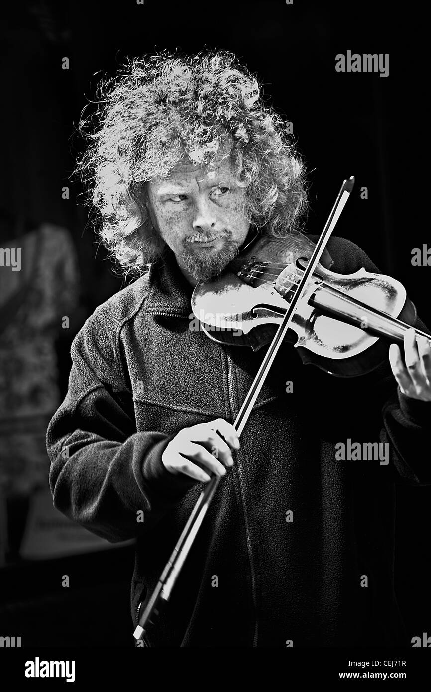 Un portrait en noir et blanc d'un homme blanc de 30 à 35 ans aux spectacles de rue,la lecture d'un violon sur les rues de Londres. Banque D'Images