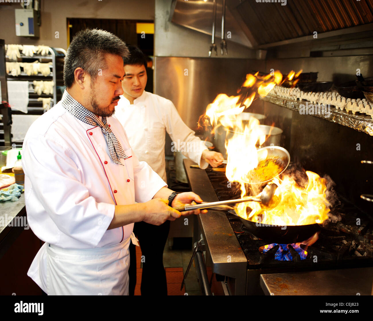 Chef de remuer la friture avec un wok, dans un restaurant coréen. Banque D'Images