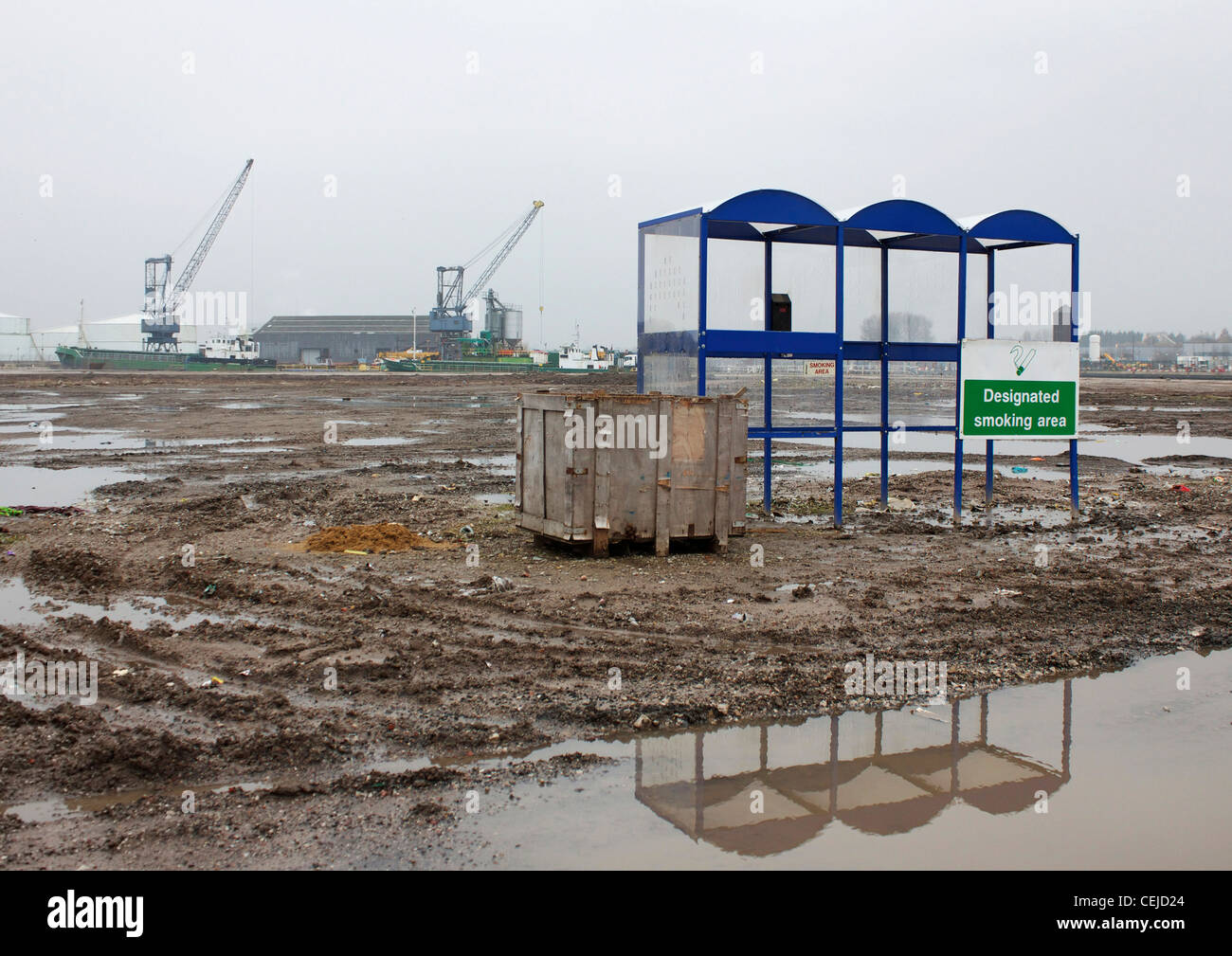 Un abri pour fumeurs tout seul dans un désert de boue et de flaques d'eau, Trafford Park, Manchester, Angleterre Banque D'Images