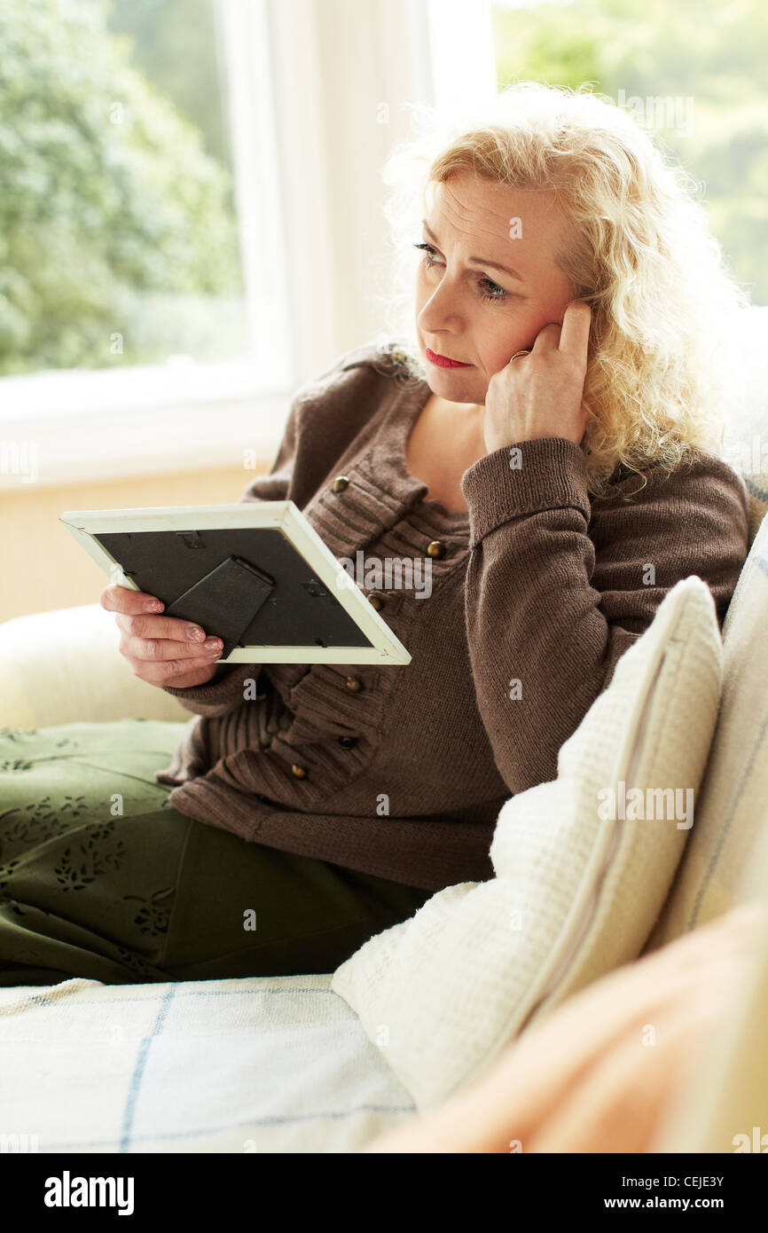 Woman looking at photograph in frame photo Banque D'Images