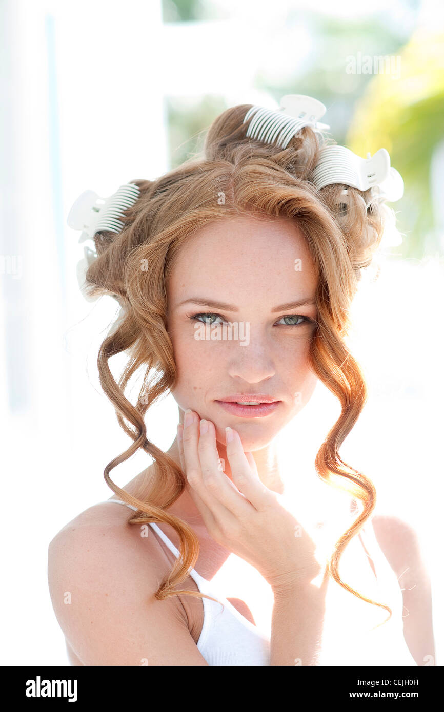 Femme cheveux rouge blanc enroulé sur les bigoudis, les cheveux ondulés se bloque à l'avant, portant un gilet blanc, souriant, looking at camera Banque D'Images