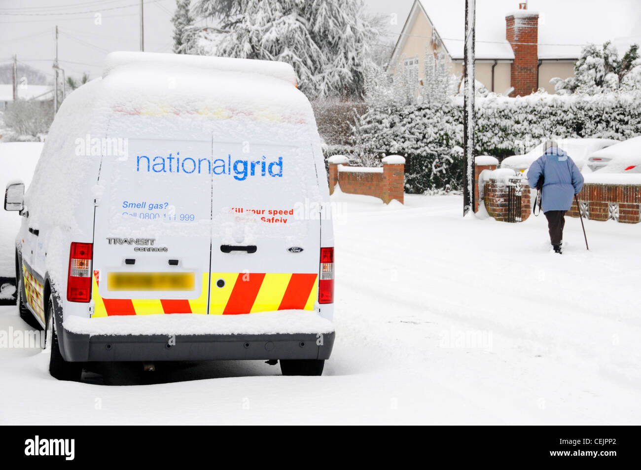 Pensionné avec bâton de marche passant National Grid van après les fortes chutes de neige Banque D'Images