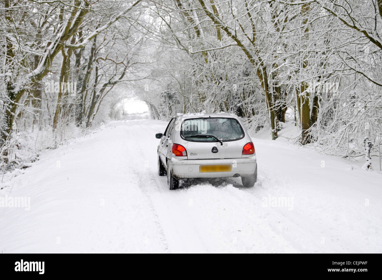 Neige scène Ford Fiesta car driving on country road lane ci-dessous de tunnel d'arbres couverts de neige en hiver wonderland Brentwood Essex England UK Banque D'Images