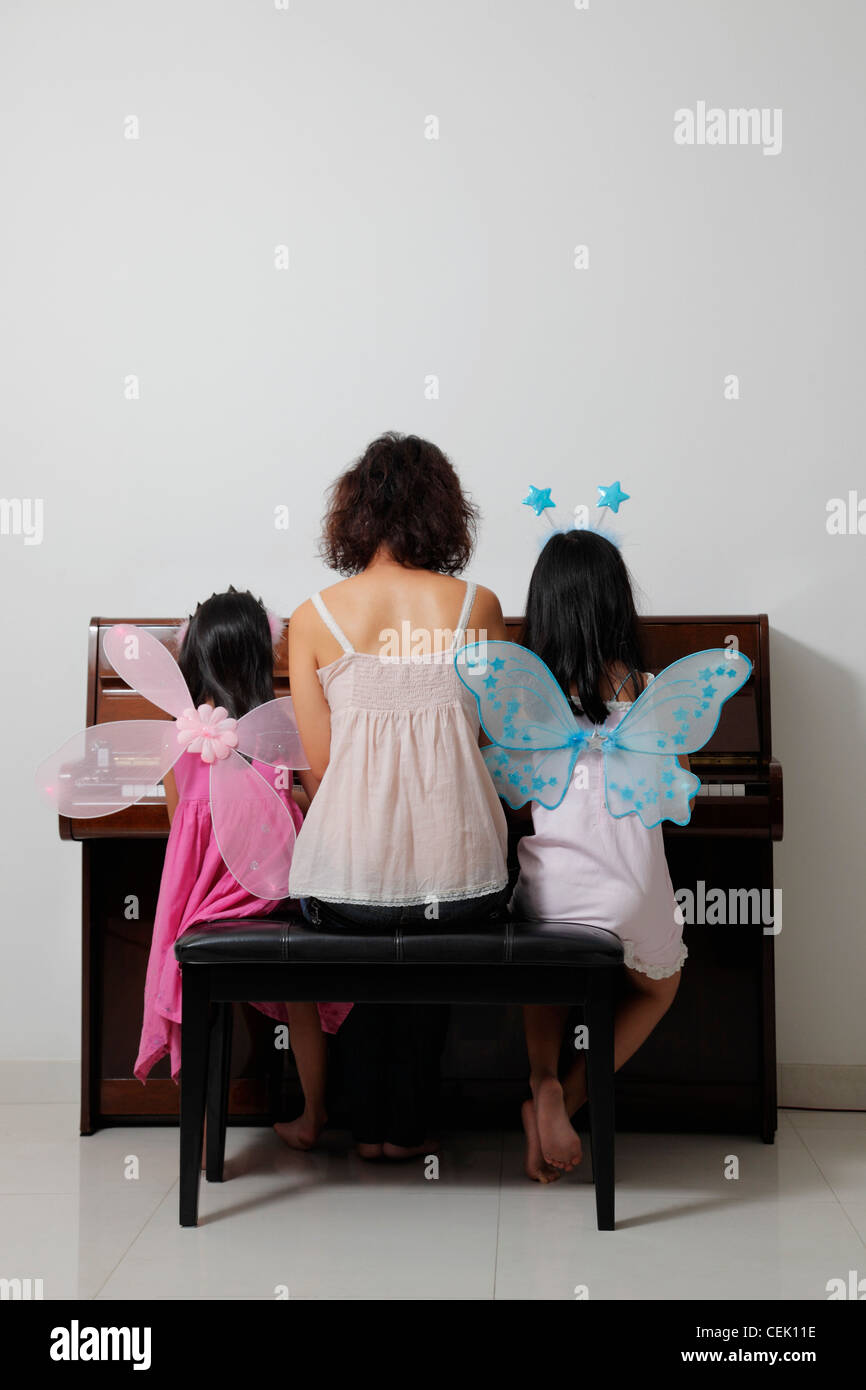 Vue arrière de la mère assise avec ses filles au piano Banque D'Images