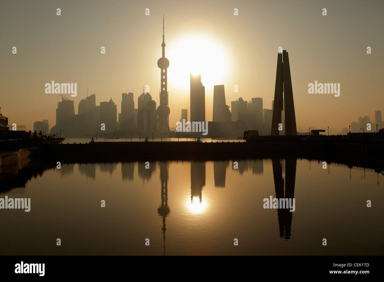 La ville de Shanghai skyline avec People's Heroes War Memorial en premier plan, reflétée dans l'eau au lever du soleil. Chine Banque D'Images