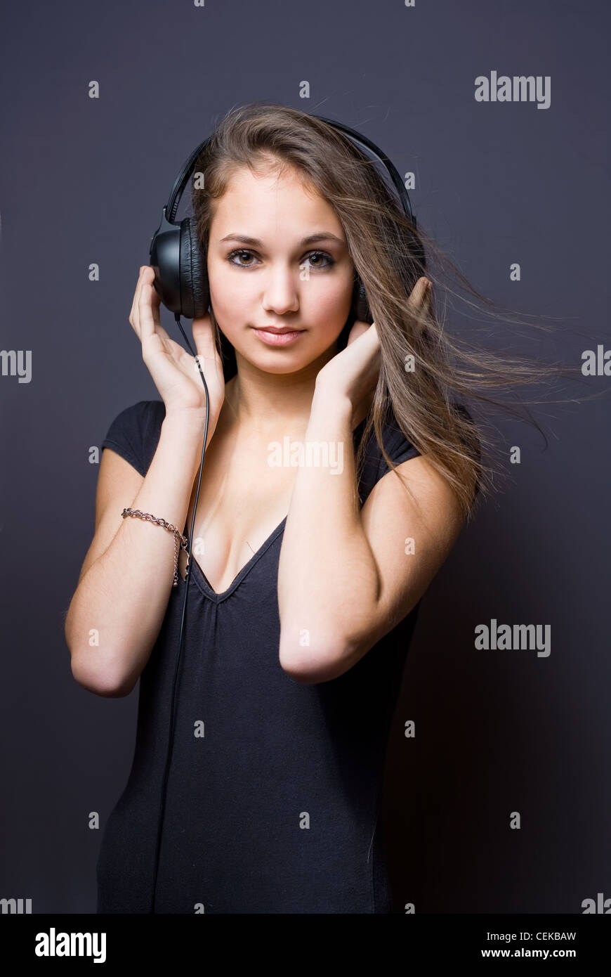 Portrait artistique d'une belle jeune brunette à écouter de la musique dans le casque. Banque D'Images