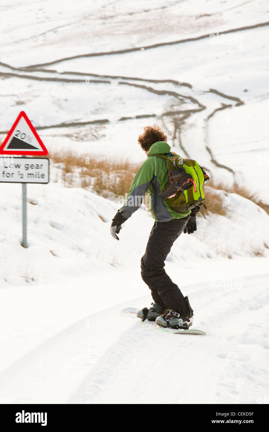 Un homme d'embarquement de la neige vers le bas depuis le sommet de la puce dans le Lake District, UK Banque D'Images