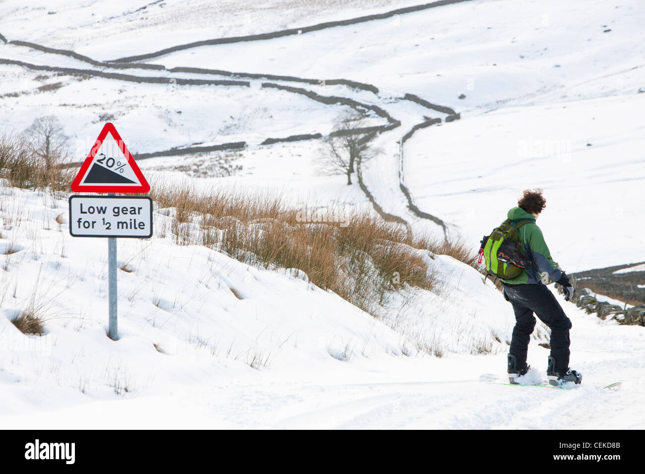 Un homme d'embarquement de la neige vers le bas depuis le sommet de la puce dans le Lake District, UK Banque D'Images