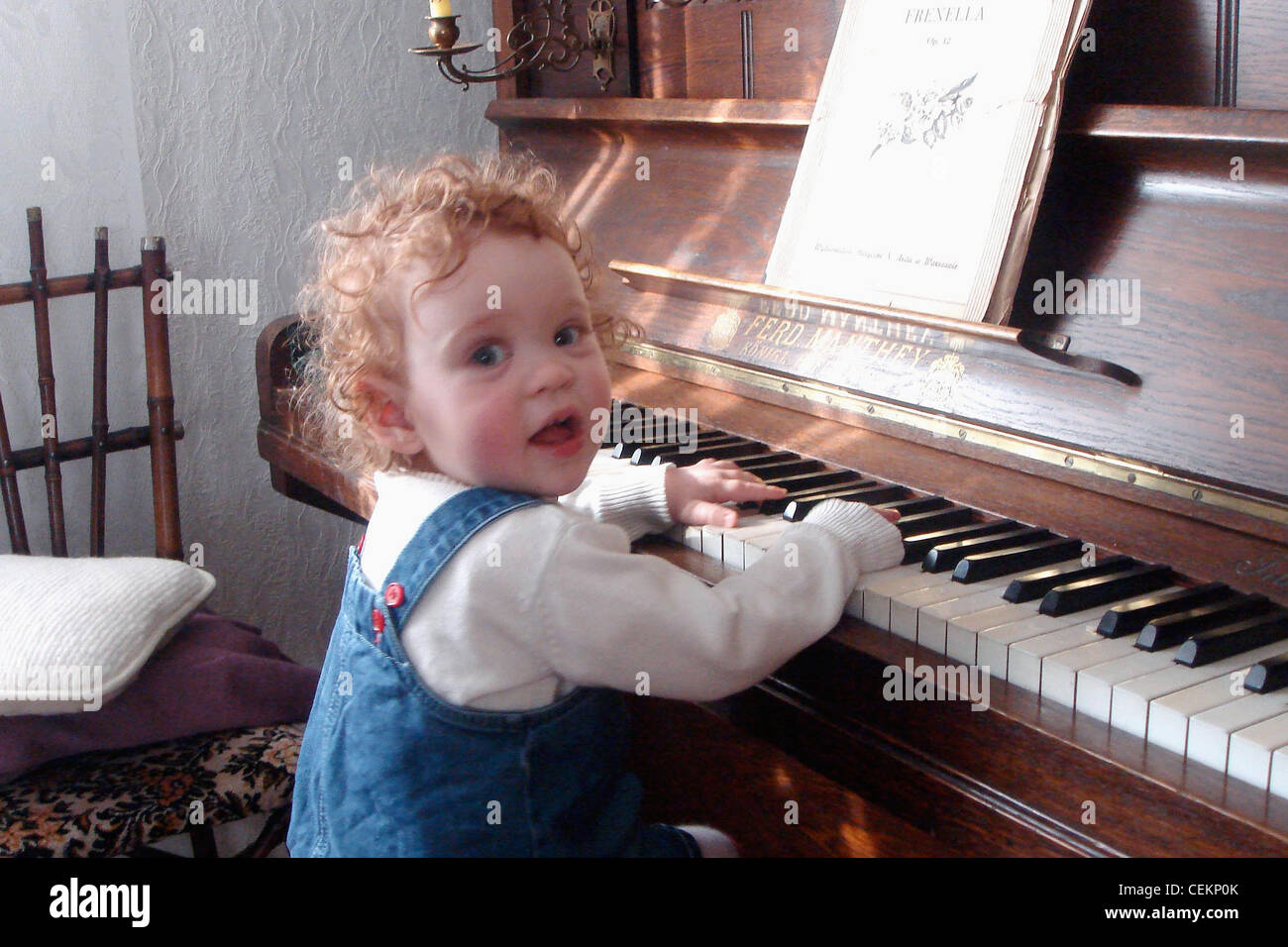 Un jeune enfant assis sur un tabouret de piano jouant au piano Banque D'Images